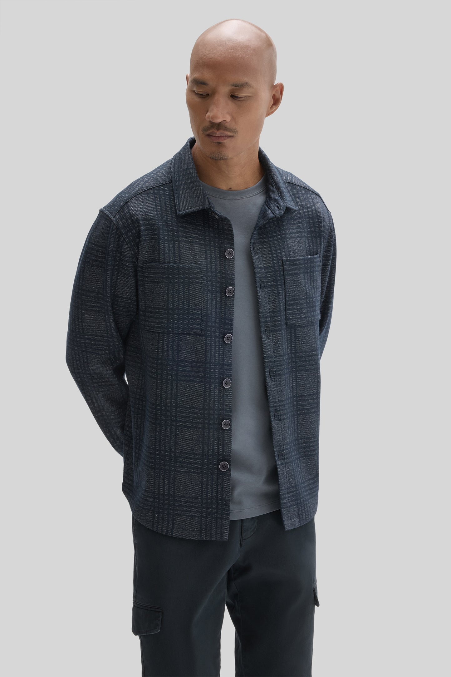 Man wearing navy plaid overshirt with button front over gray t-shirt and black cargo pants.