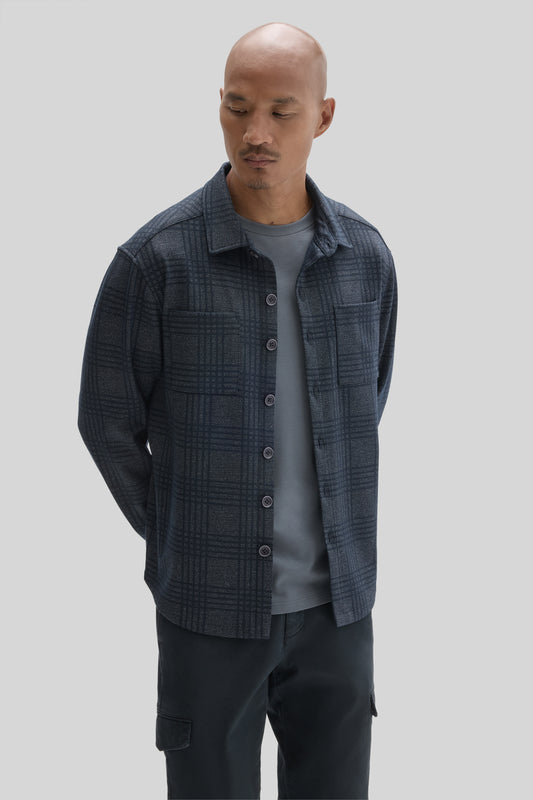 Man wearing navy plaid overshirt with button front over gray t-shirt and black cargo pants.