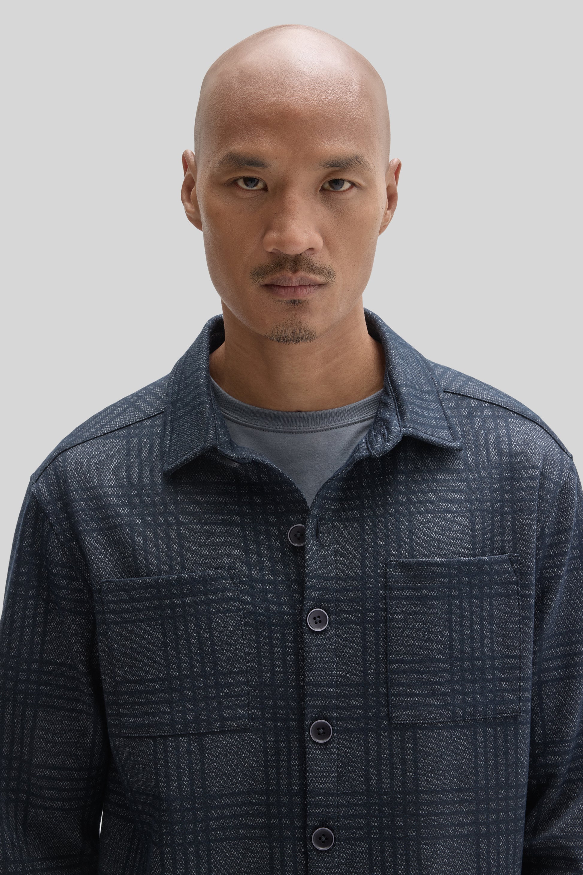Man wearing dark navy plaid overshirt with button front over gray t-shirt.