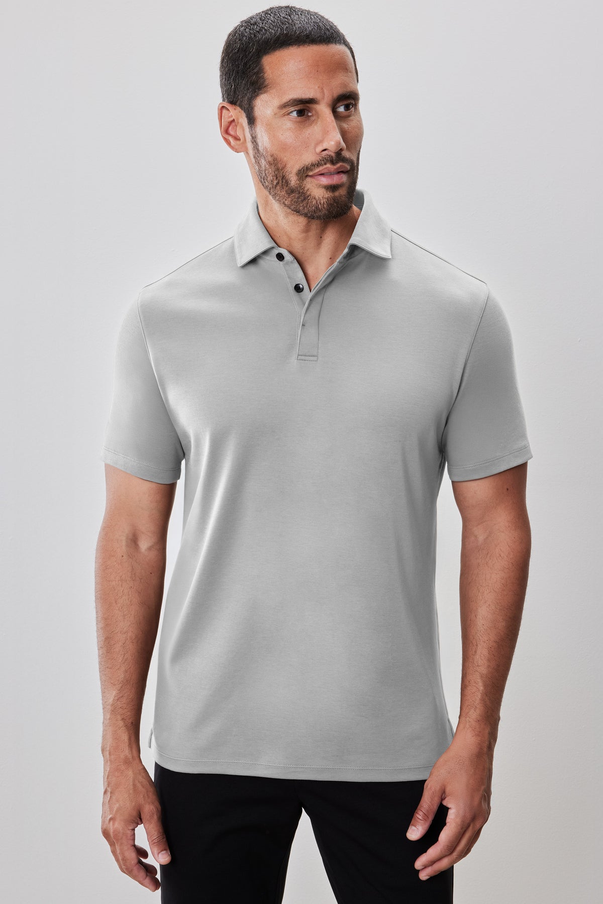 Light gray polo shirt with short sleeves, collar, and covered placket front on male model wearing black pants.
