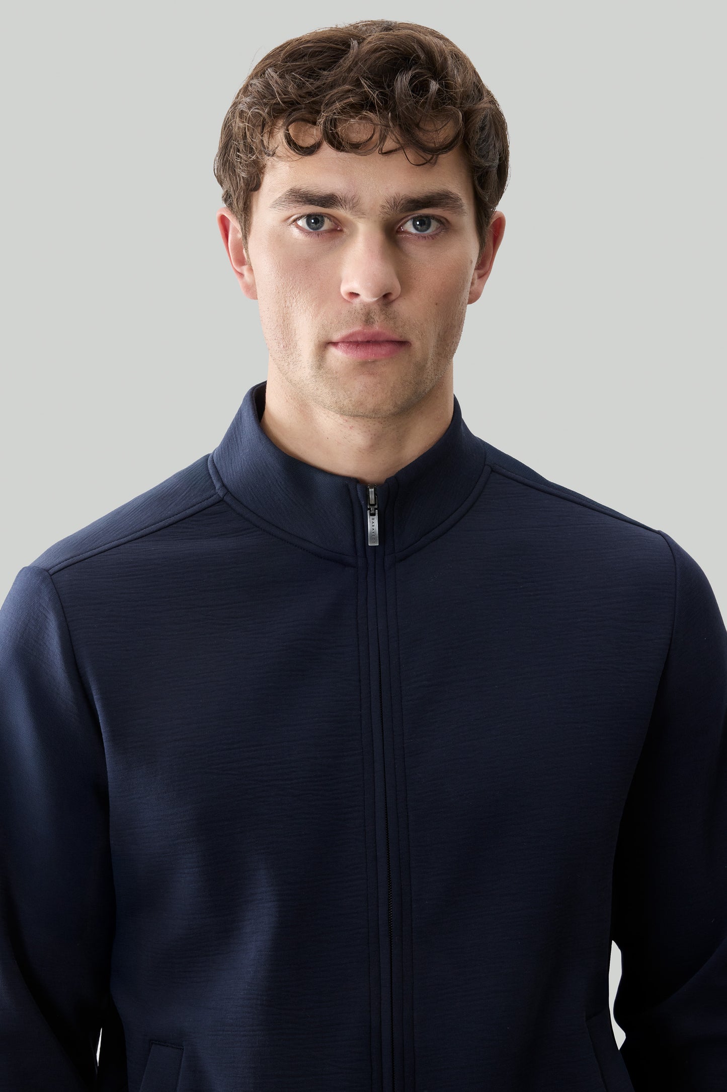 Man wearing dark navy long sleeve full zip jacket with textured fabric.