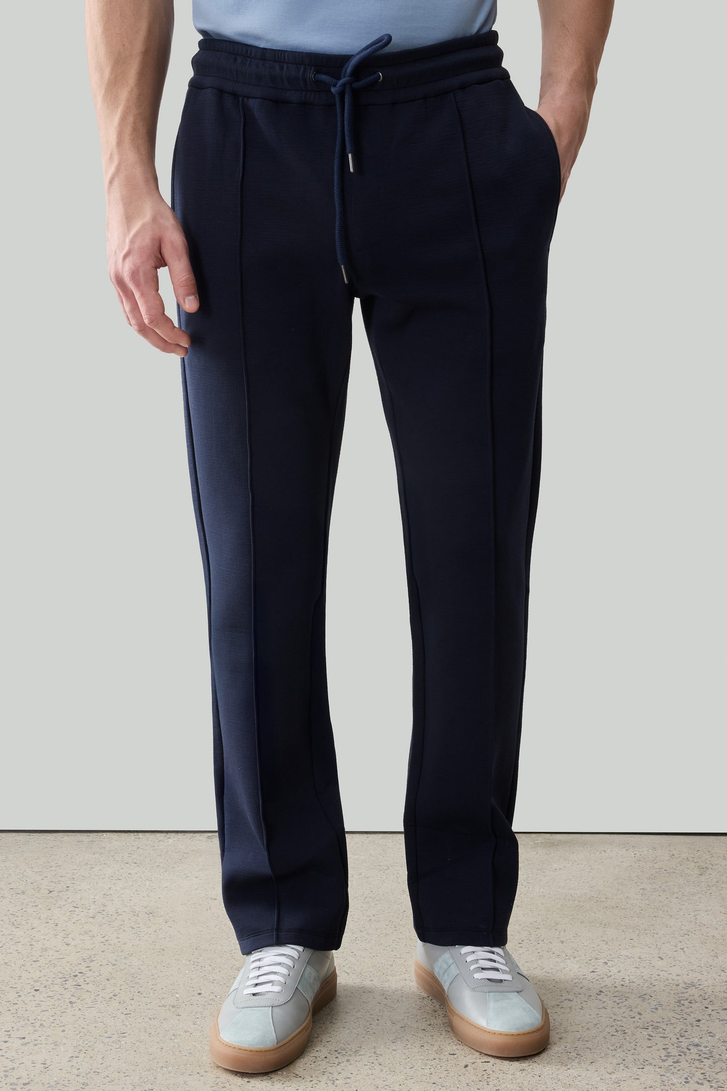 Navy jogger pants with drawstring waist and side stripe detail, paired with white sneakers.