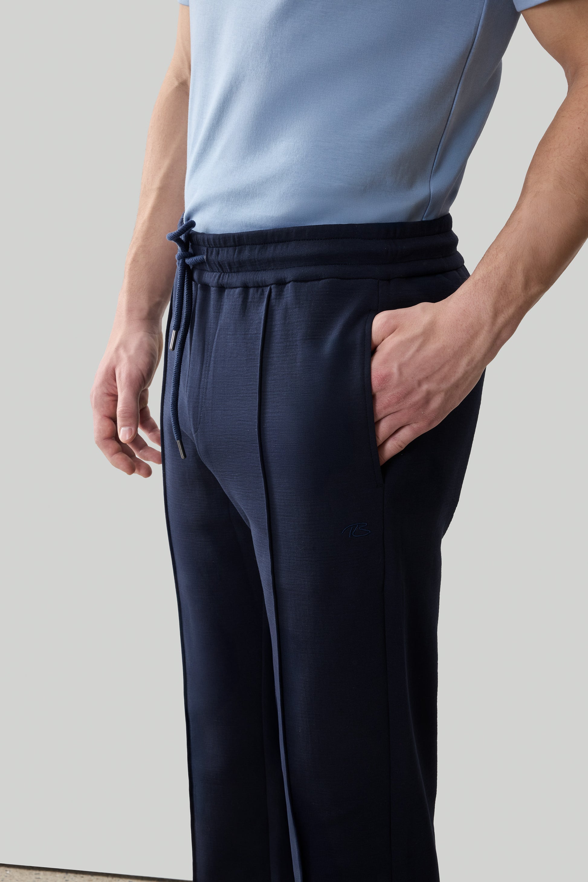 Navy jogger pants with drawstring waist and side pockets, worn with light blue t-shirt.