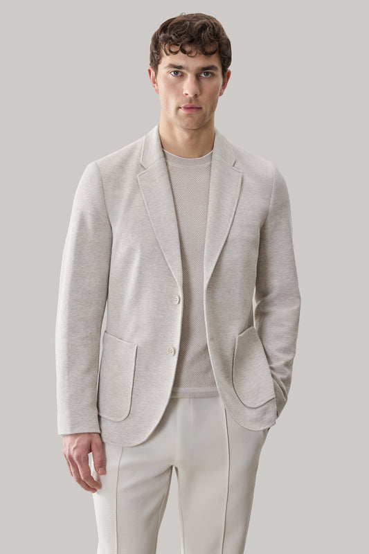 Man wearing light gray sportcoat with notch lapels and patch pockets over a ribbed knit shirt.
