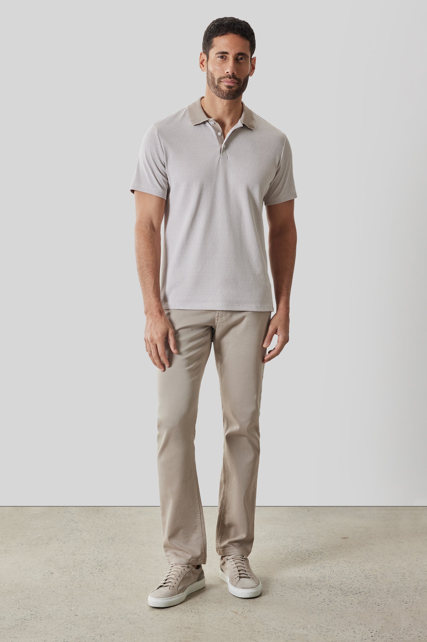 Man wearing light gray short-sleeve polo shirt with collar and button front, paired with beige chinos and white sneakers.
