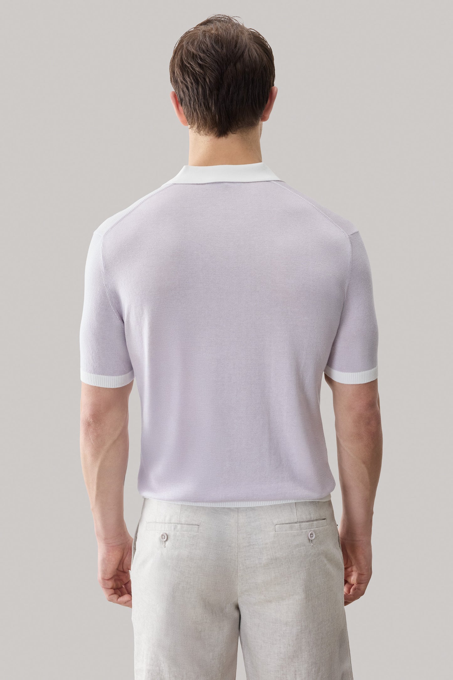 Light purple sweater polo with white collar and ribbed sleeve cuffs, paired with beige trousers.