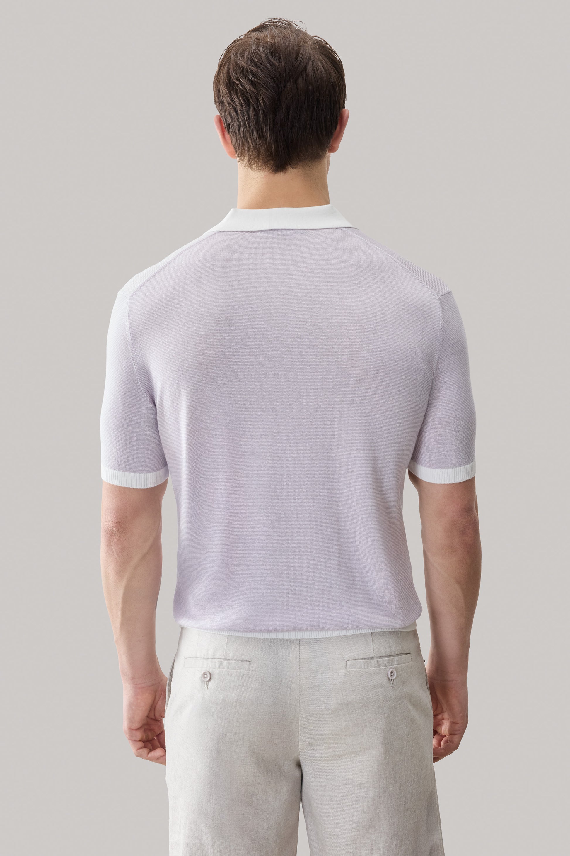 Light purple sweater polo with white collar and ribbed sleeve cuffs, paired with beige trousers.