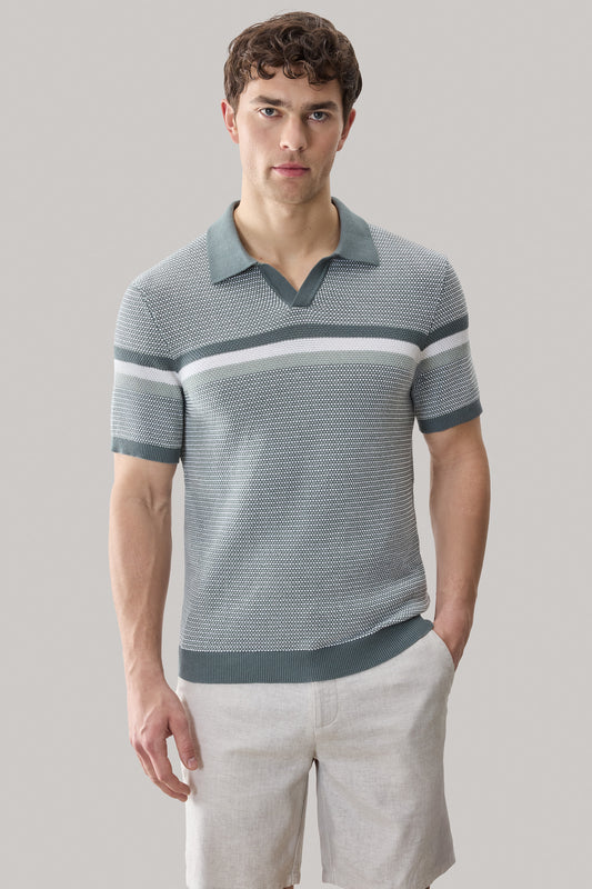 Man wearing gray and white striped short-sleeve polo sweater with open collar and light tan shorts.