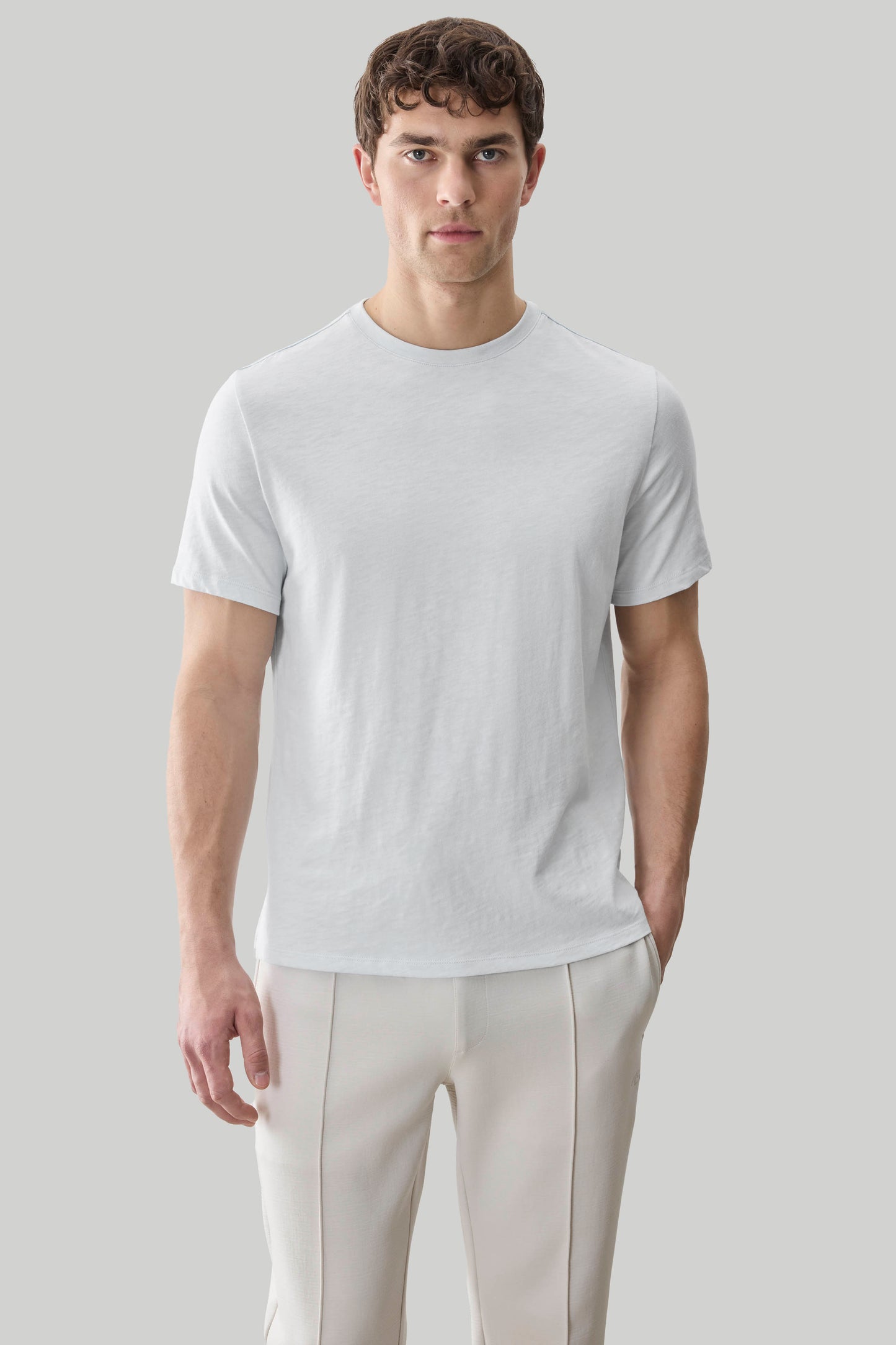 Man wearing a light gray short-sleeve crew neck tee with textured fabric paired with cream-colored pants.