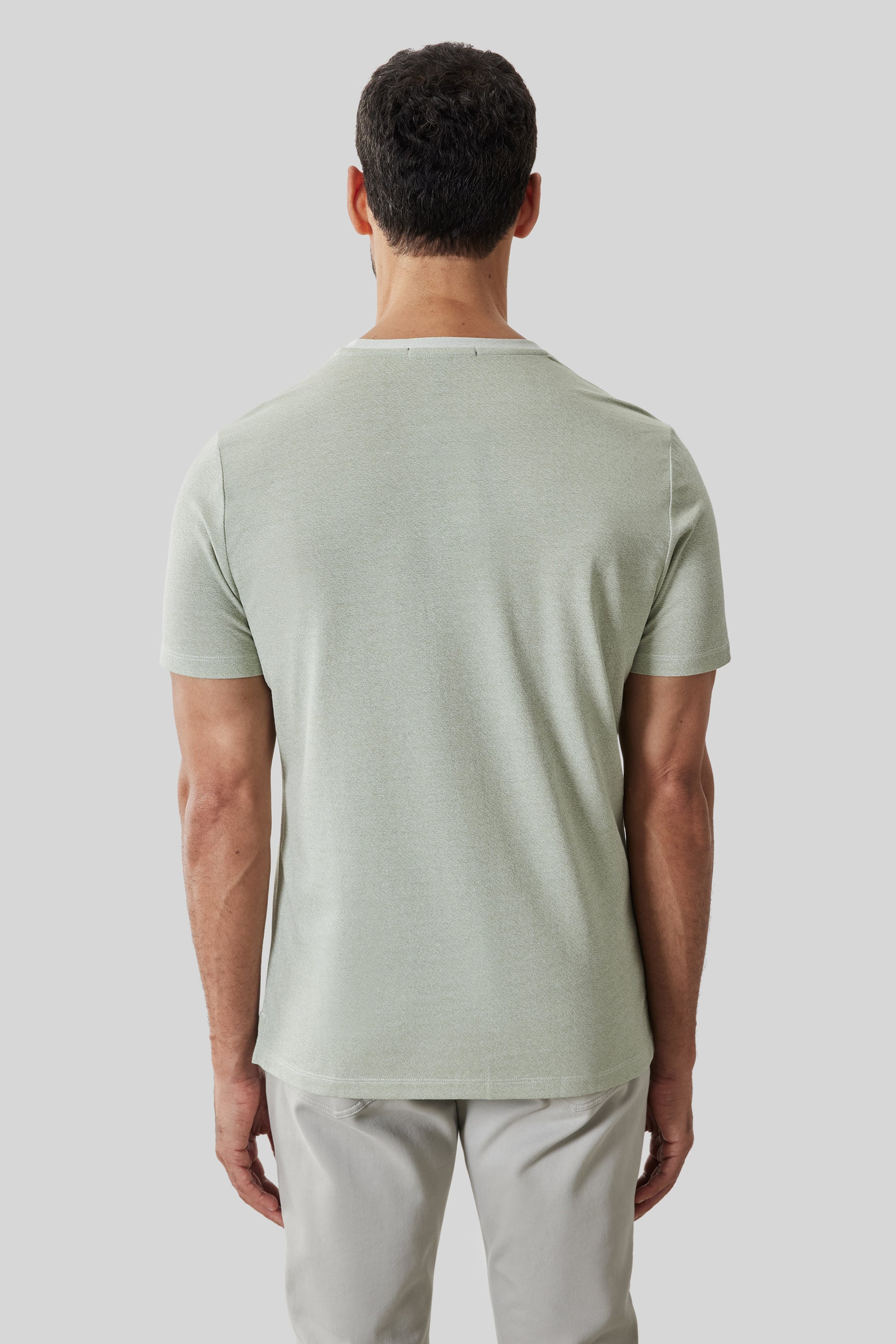 Man wearing light green short-sleeve t-shirt, back view.