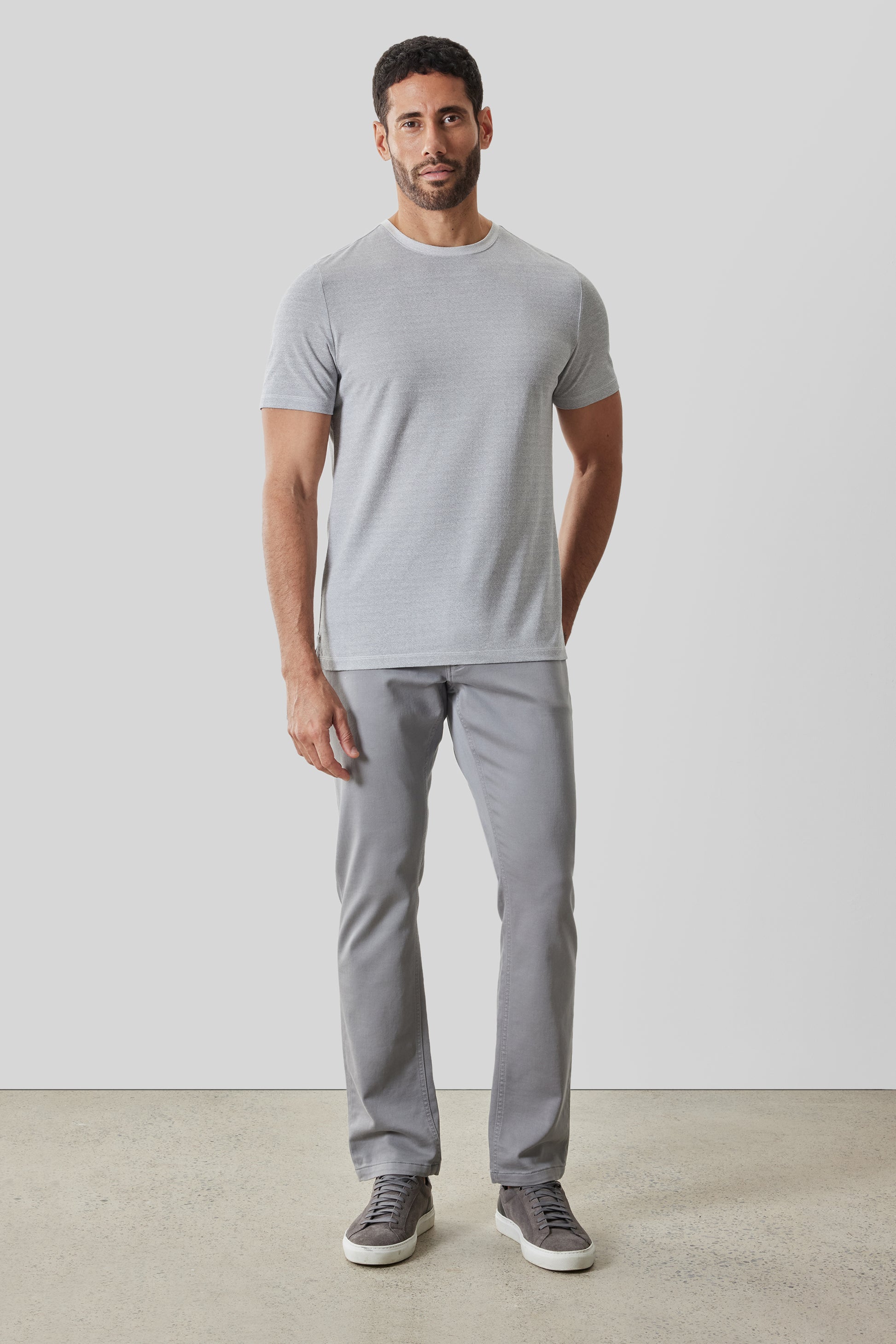 Man wearing light gray short-sleeve crew neck t-shirt with gray pants and dark sneakers.
