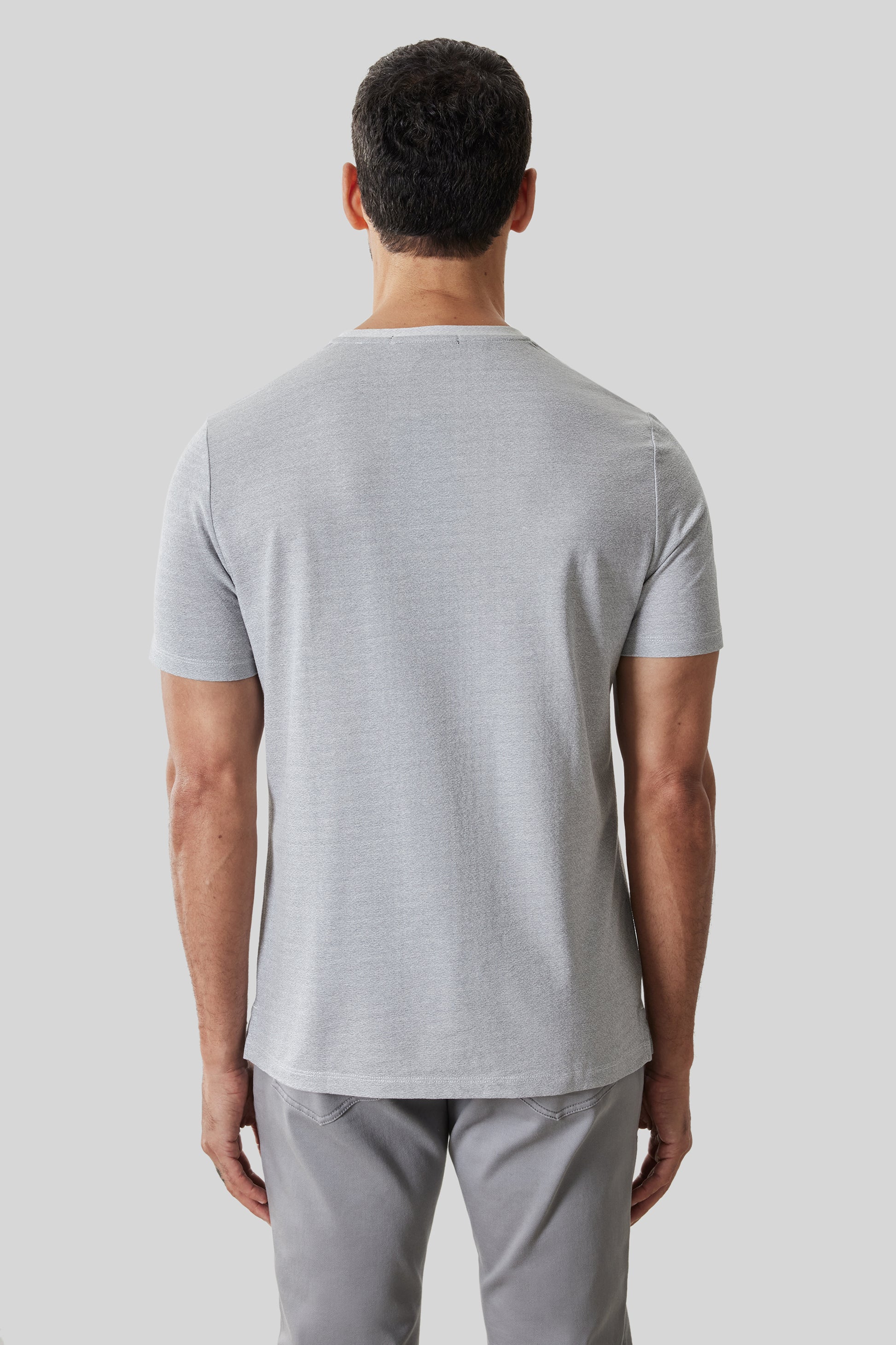 Man wearing light gray short-sleeve t-shirt, back view.