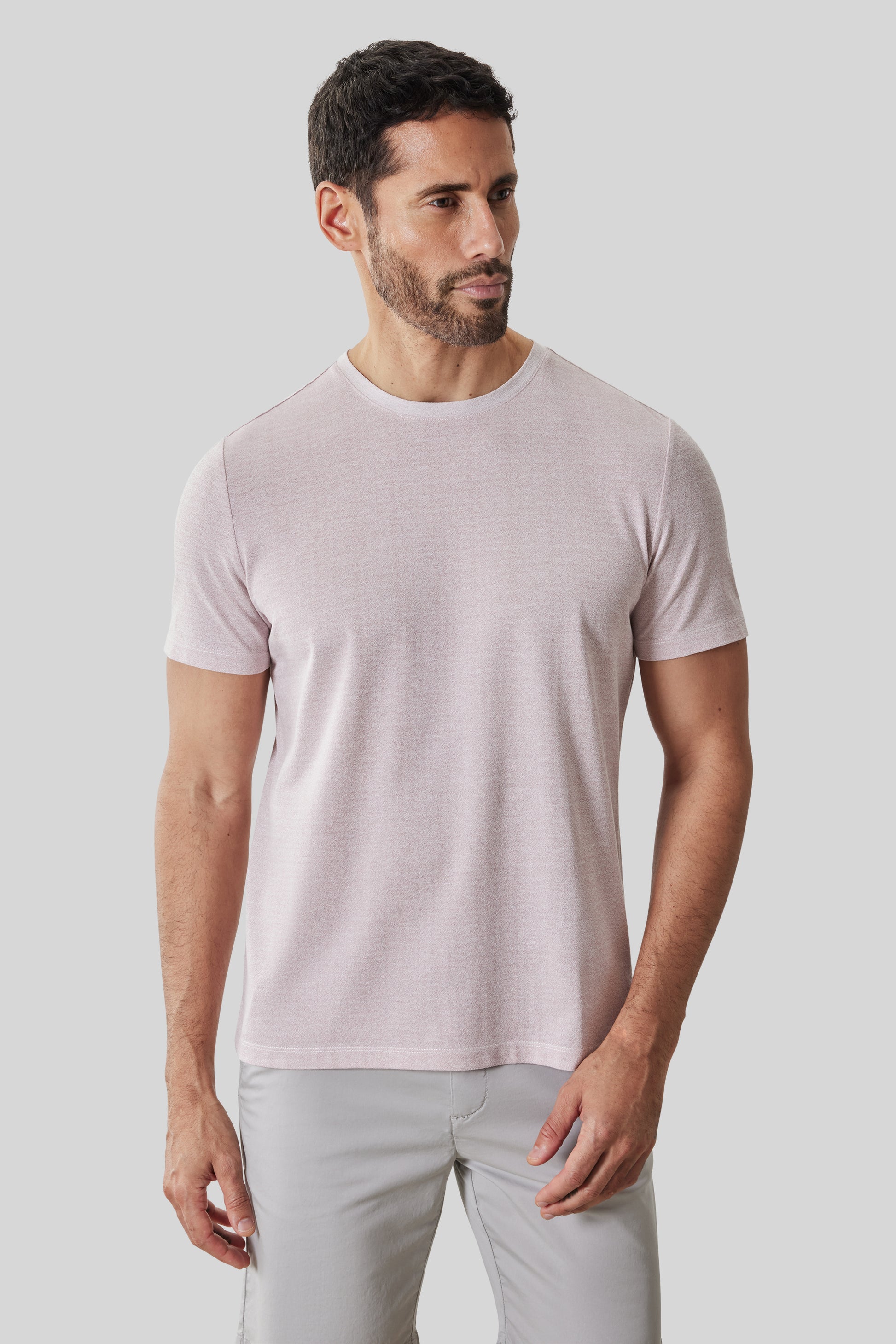 Man wearing light pink short-sleeve crew neck tee with light gray pants.