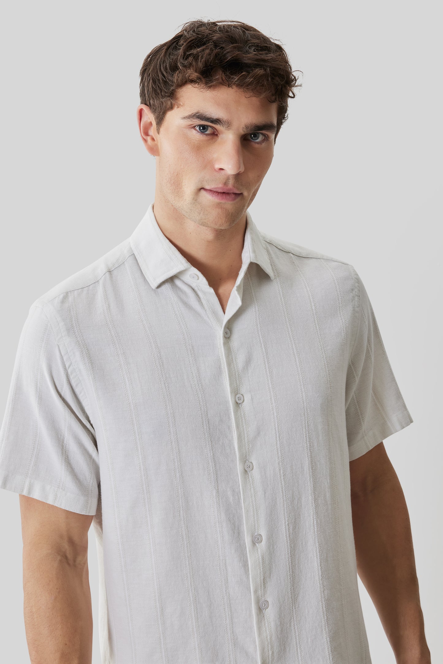 Man wearing white short-sleeved button-up shirt with textured fabric and collar.