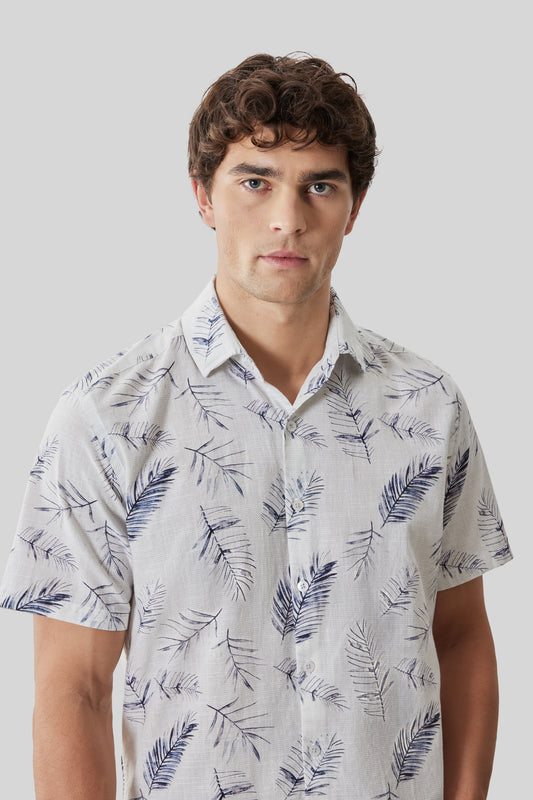 Man wearing white short-sleeve shirt with blue feather print pattern and collar.