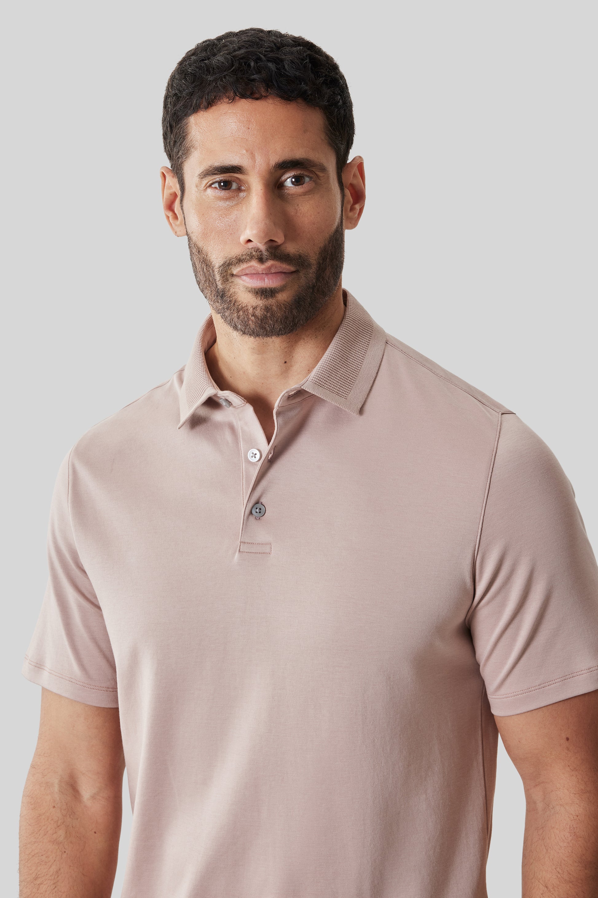 Man wearing a taupe polo shirt with textured collar and short sleeves.