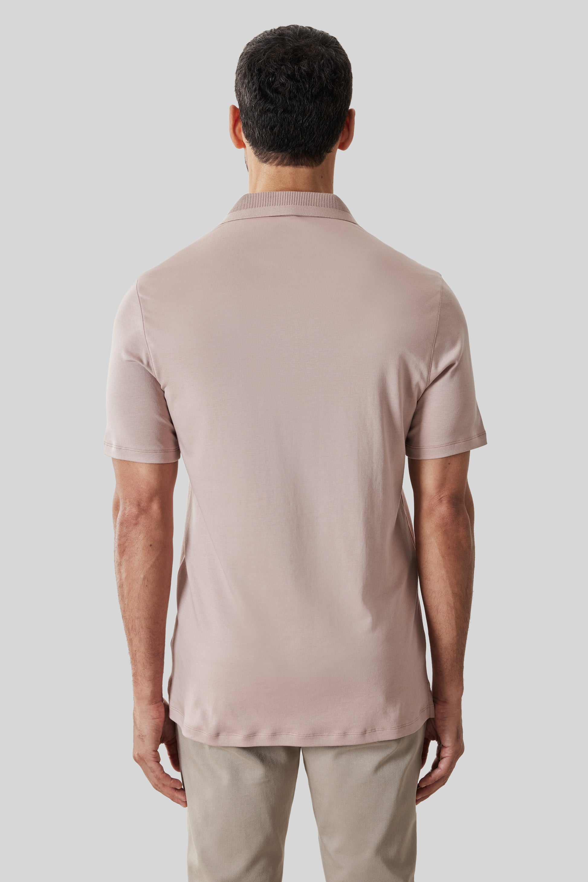Man wearing beige short-sleeve polo shirt with textured ribbed collar, shown from back.