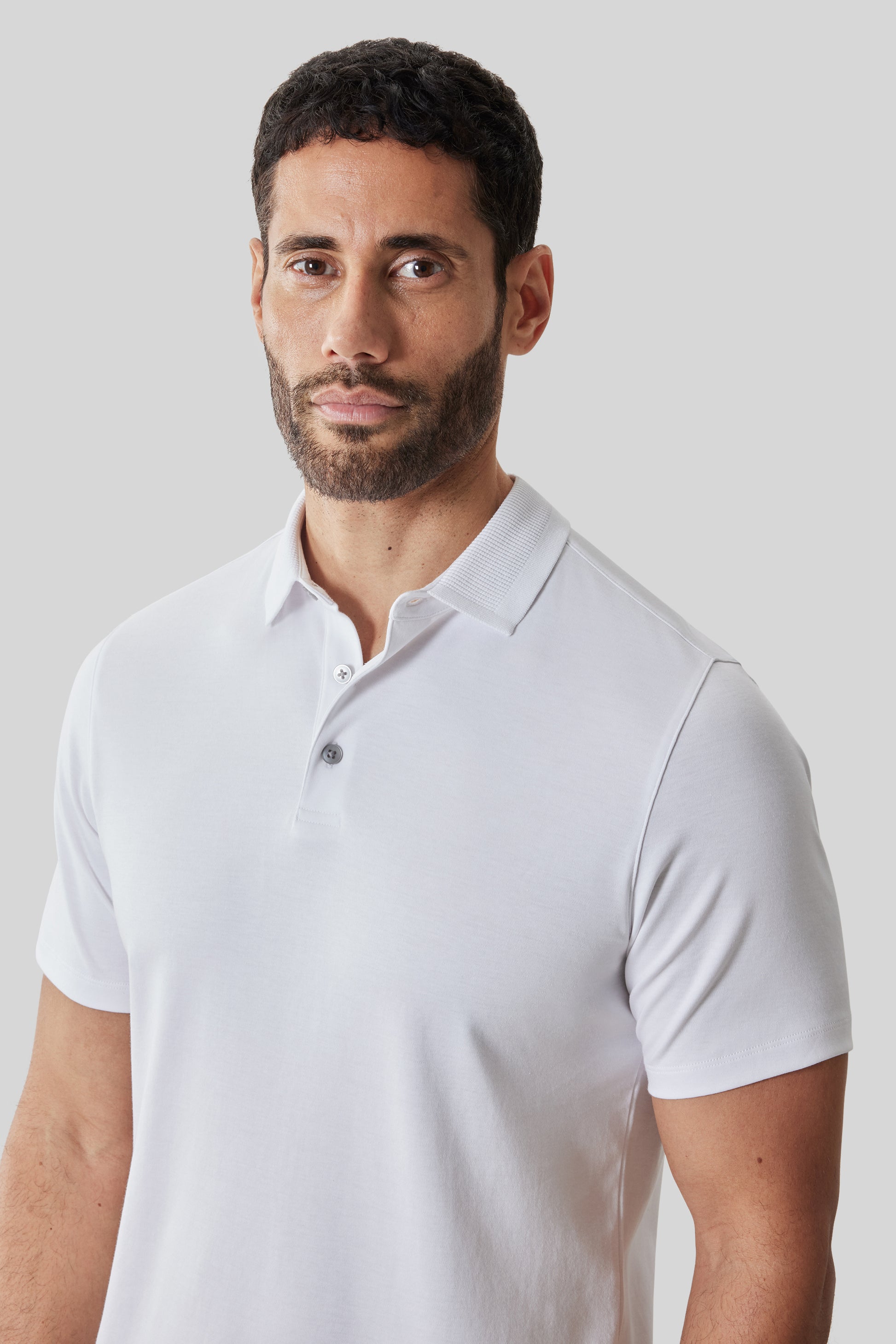 White short-sleeve polo shirt with textured collar and button front, worn by man.
