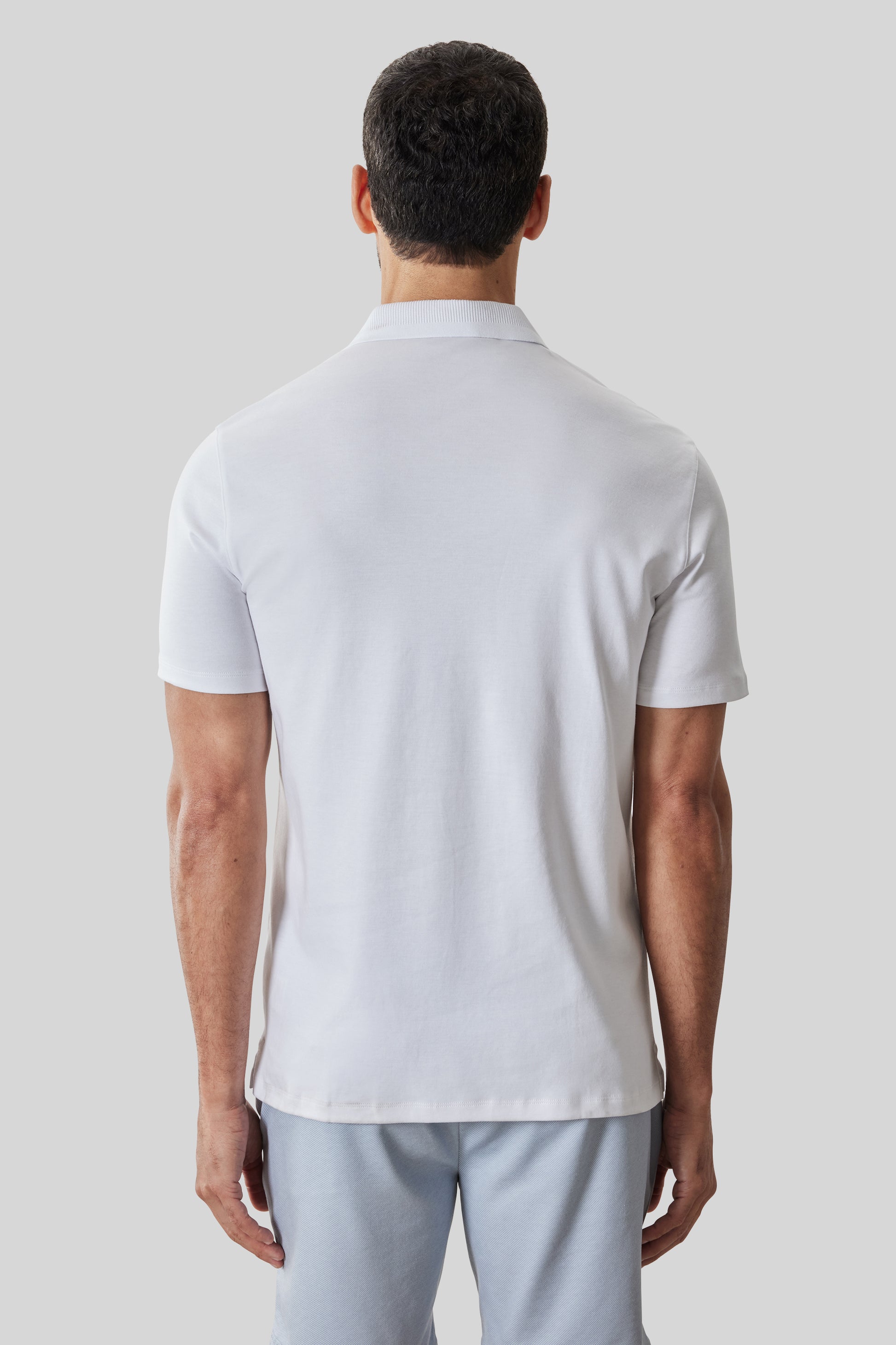White polo shirt with textured collar and short sleeves, shown on model from back view.
