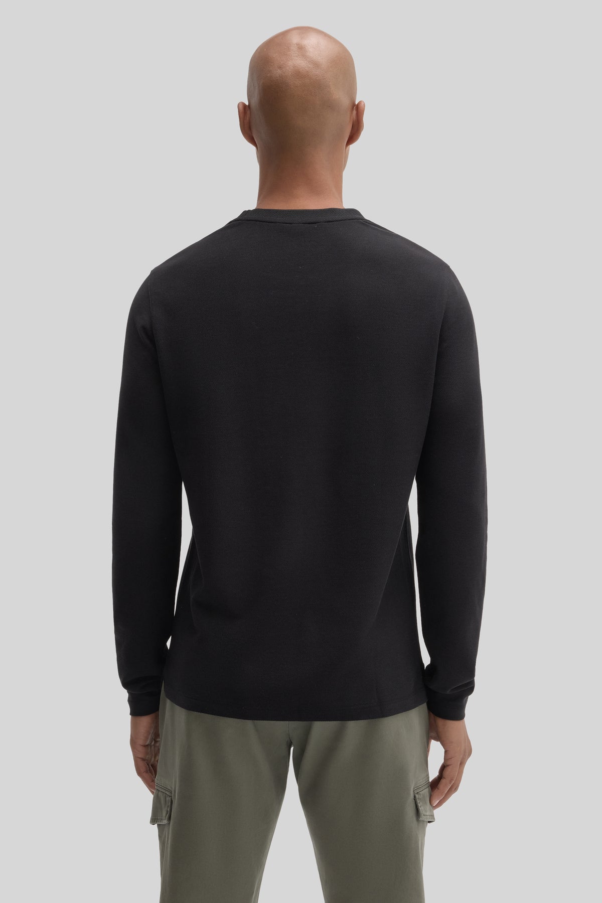 Black long sleeve crew neck sweatshirt worn with sage green cargo pants, back view.