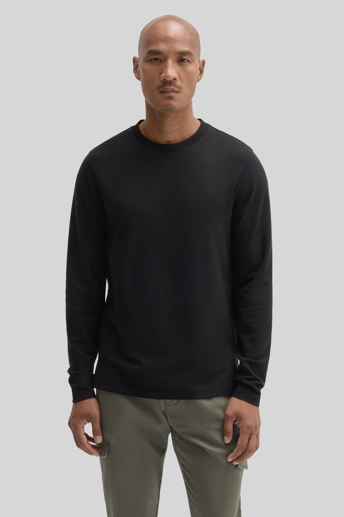 Man wearing black crew neck long sleeve shirt with khaki pants.