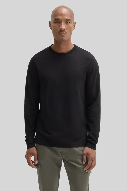 Man wearing black crew neck long sleeve shirt with khaki pants.
