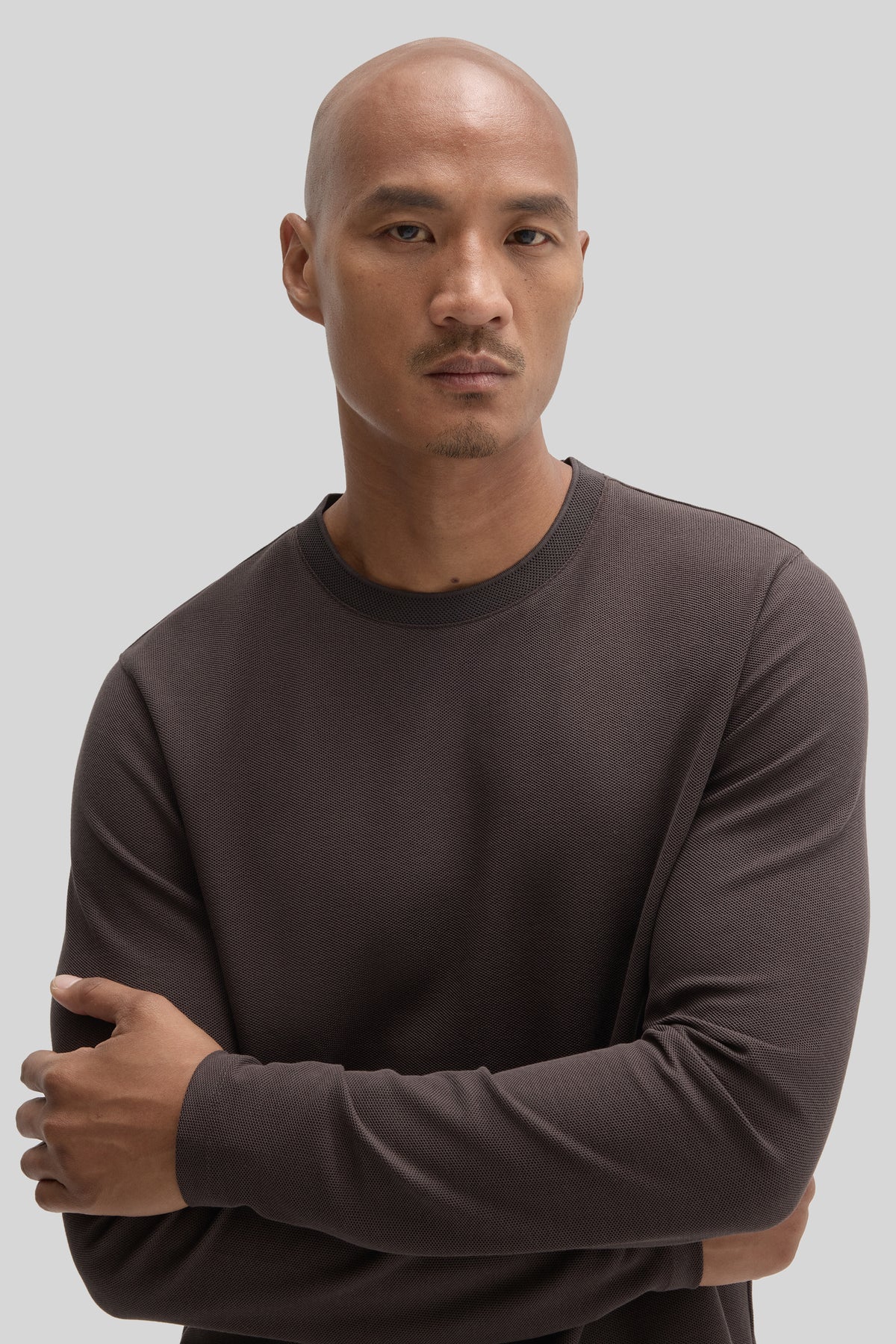 Man wearing charcoal long sleeve crew neck shirt with ribbed texture.