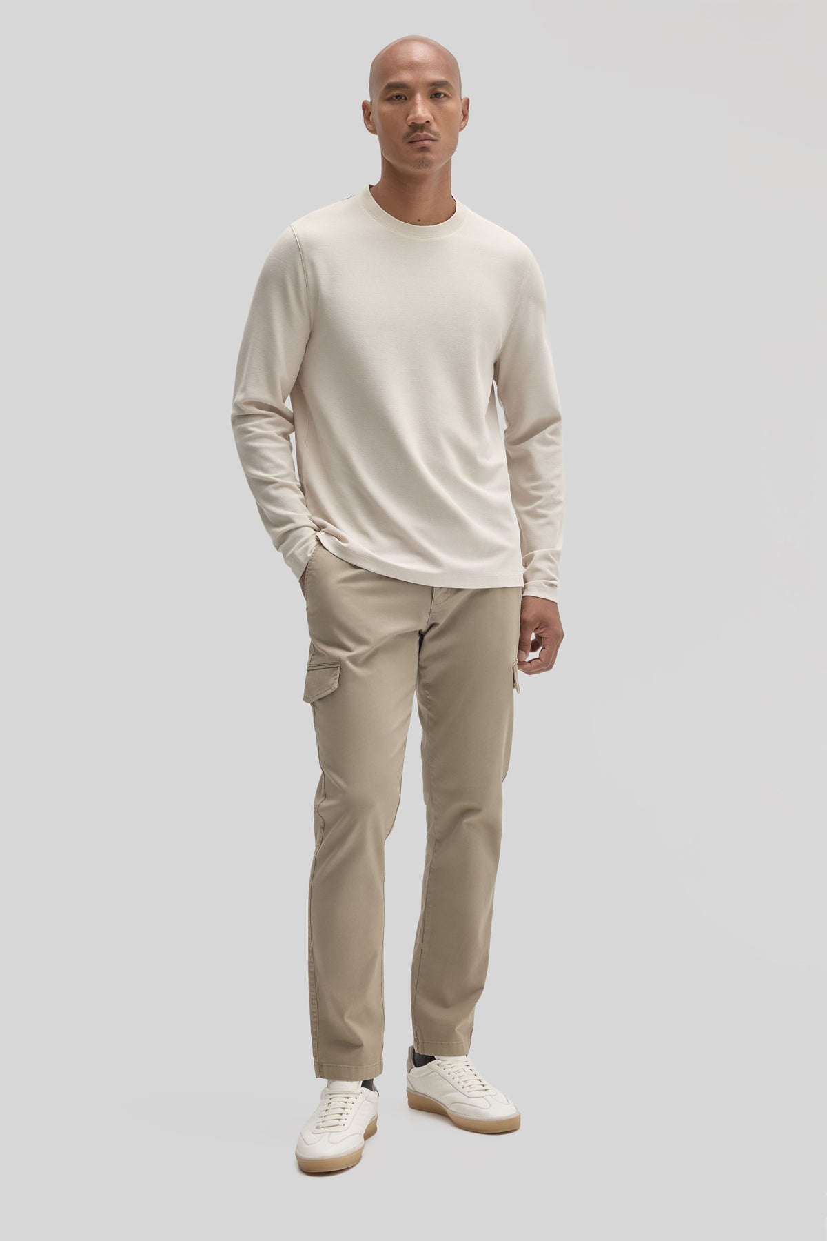 Man wearing cream long sleeve crew neck shirt and beige cargo pants with white sneakers.