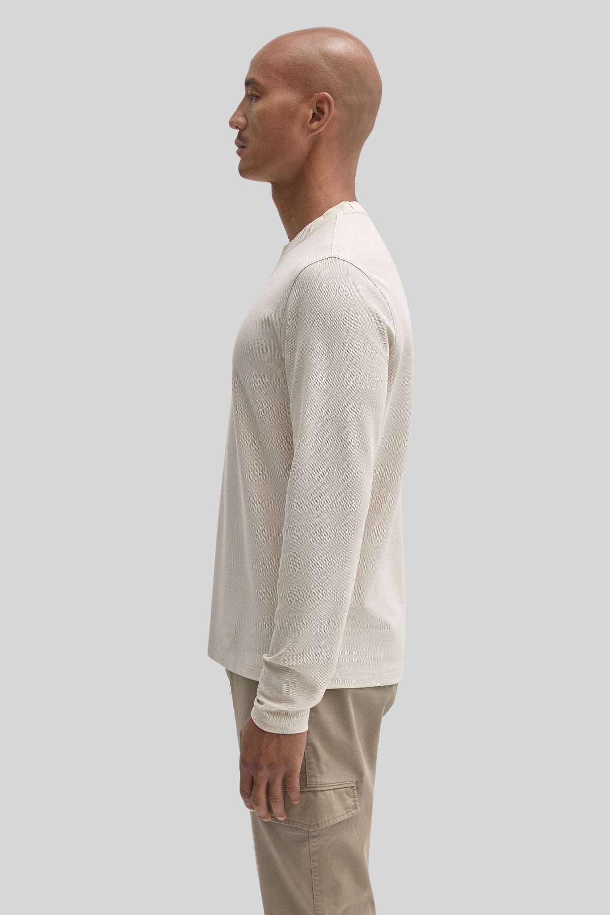 Cream long sleeve crew neck shirt on model shown from the side.