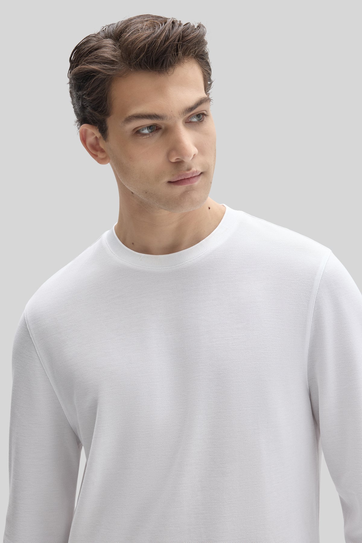 Man wearing white long sleeve crew neck sweatshirt with ribbed texture.