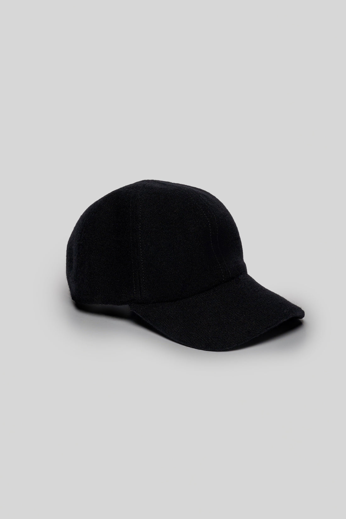 Black knit baseball cap with rounded crown and curved bill on neutral background.