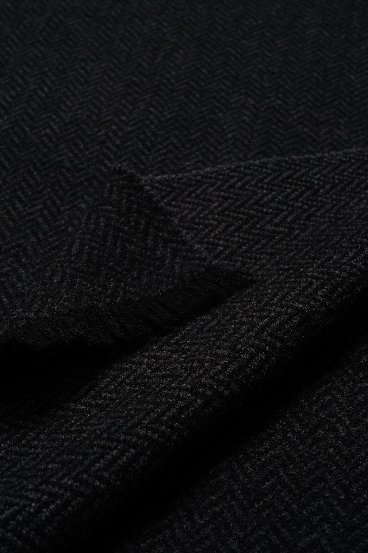 Black cashmere scarf with herringbone weave texture and soft finish.