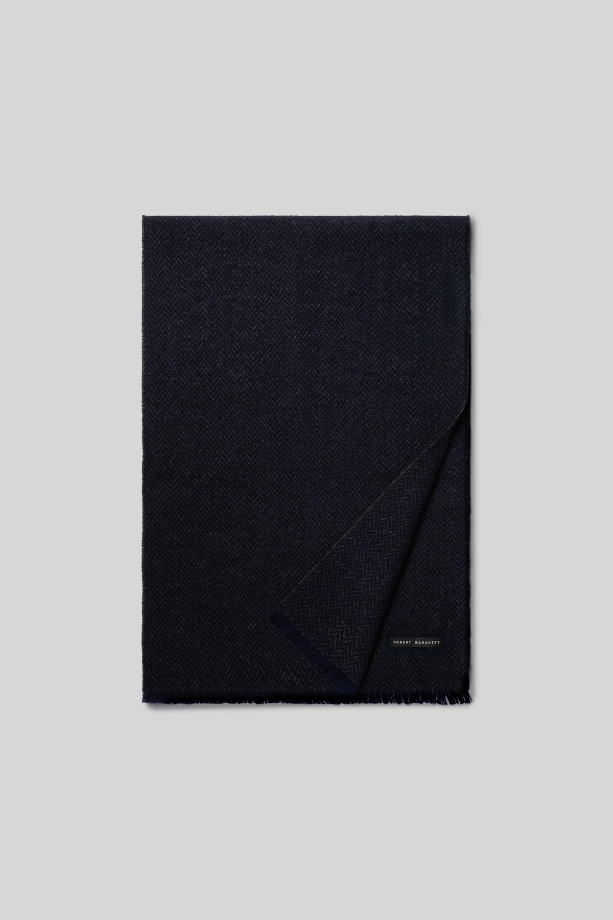 Dark navy cashmere scarf with herringbone weave pattern and fringe trim, partially folded.