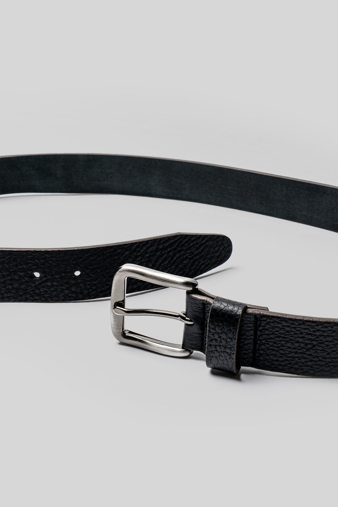 Black leather belt with textured surface and silver-toned rectangular buckle with prong fastening.