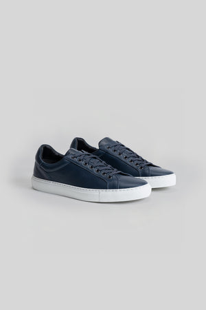 Navy blue leather low-top sneakers with white rubber sole and dark laces, shown as a pair.