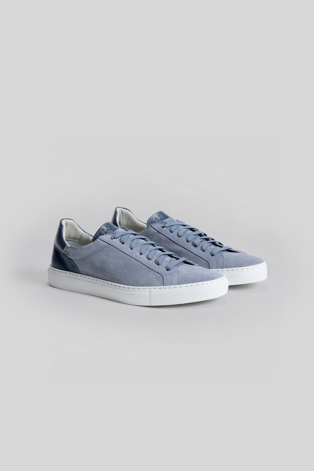 Blue and navy sneakers with white rubber sole and lace-up closure shown from the side.