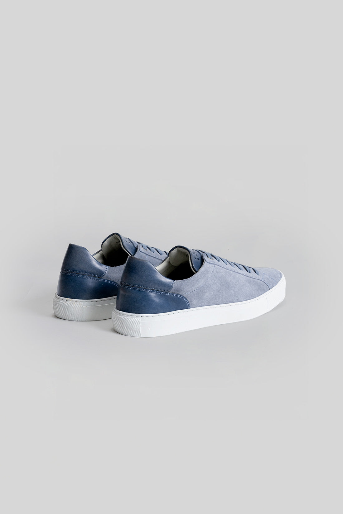 Blue and navy sneaker with white sole, shown from rear three-quarter view.