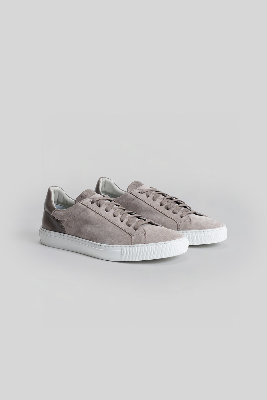 Gray suede sneakers with white rubber sole and lace-up front closure.