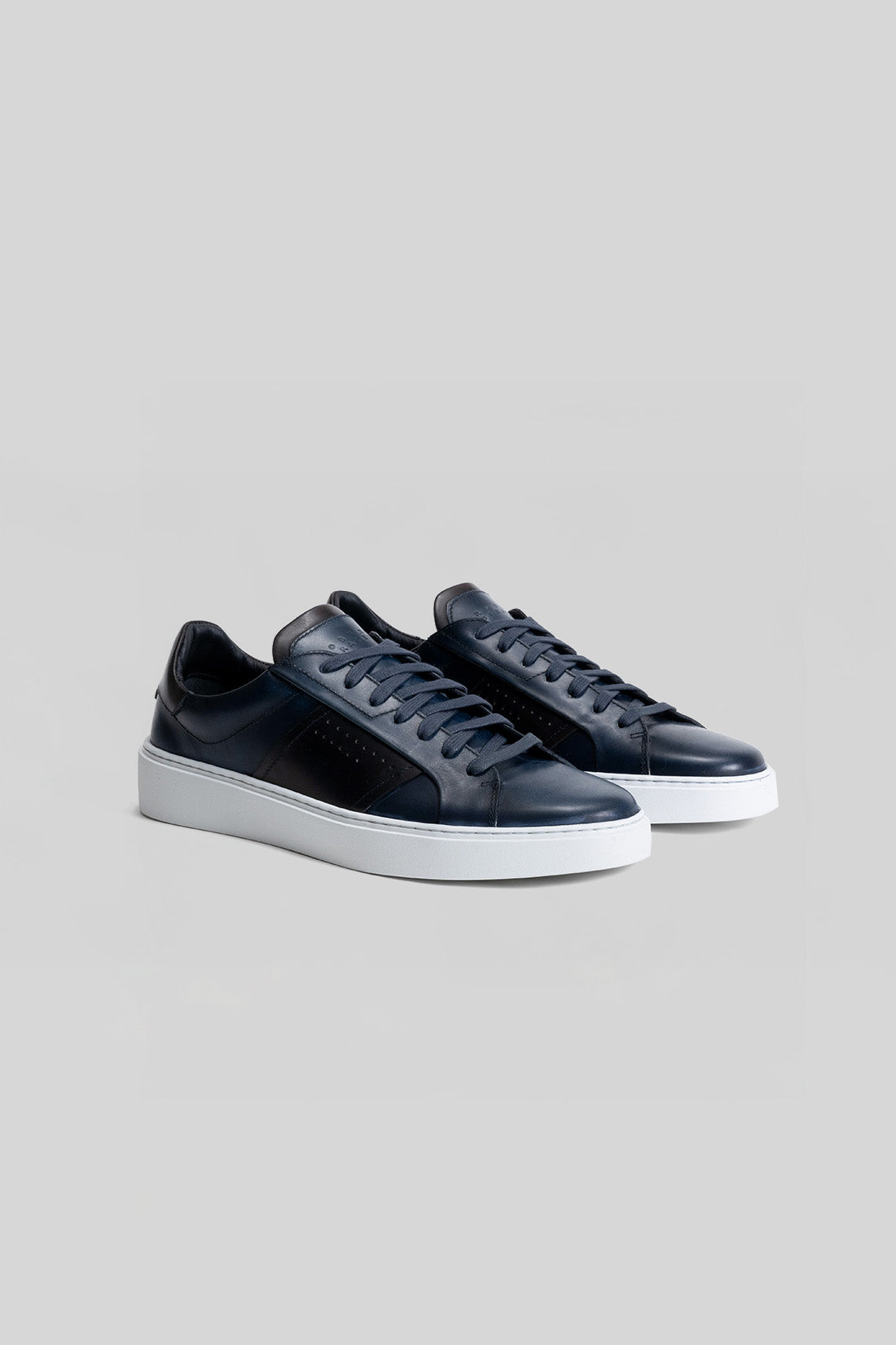 Pair of black leather lace-up sneakers with white platform sole, shown from a three-quarter view angle.