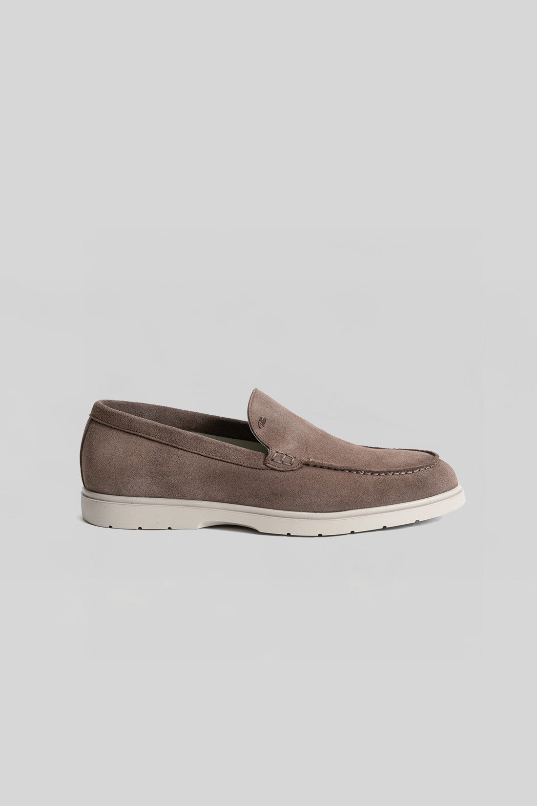 Taupe suede loafer with cream rubber sole and stitched detail on upper.