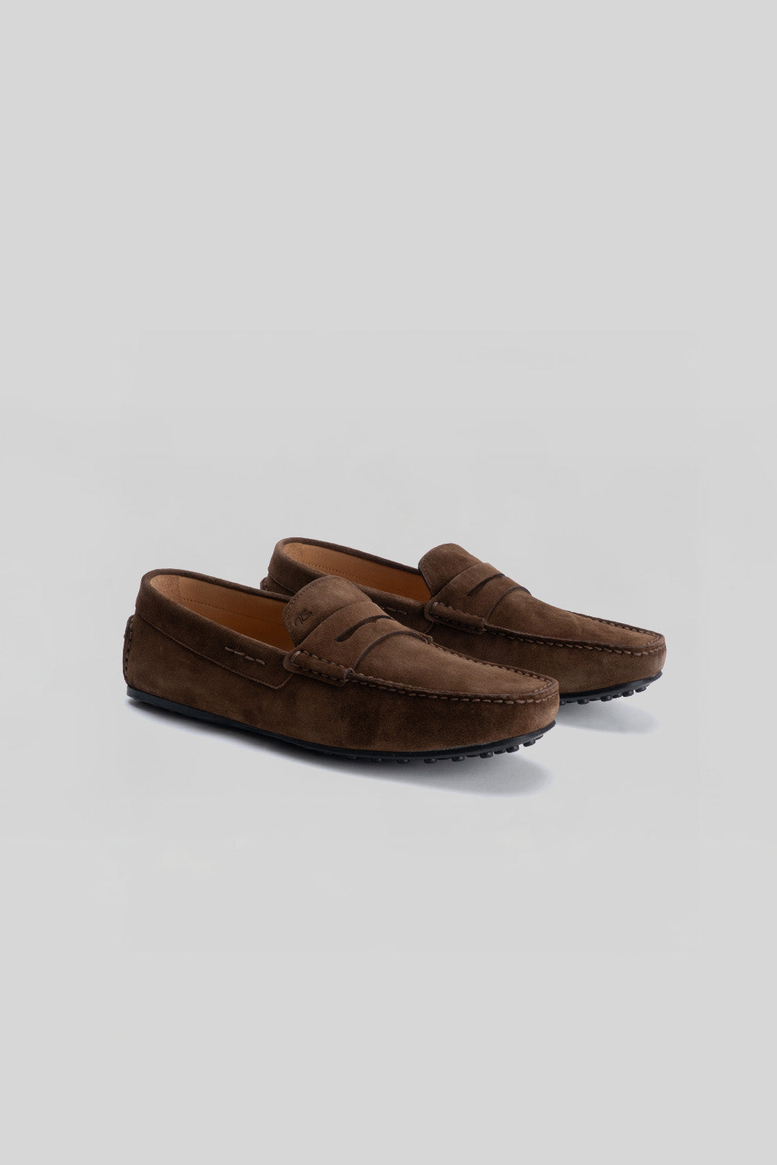 Pair of brown suede loafers with penny strap detail and textured rubber sole.