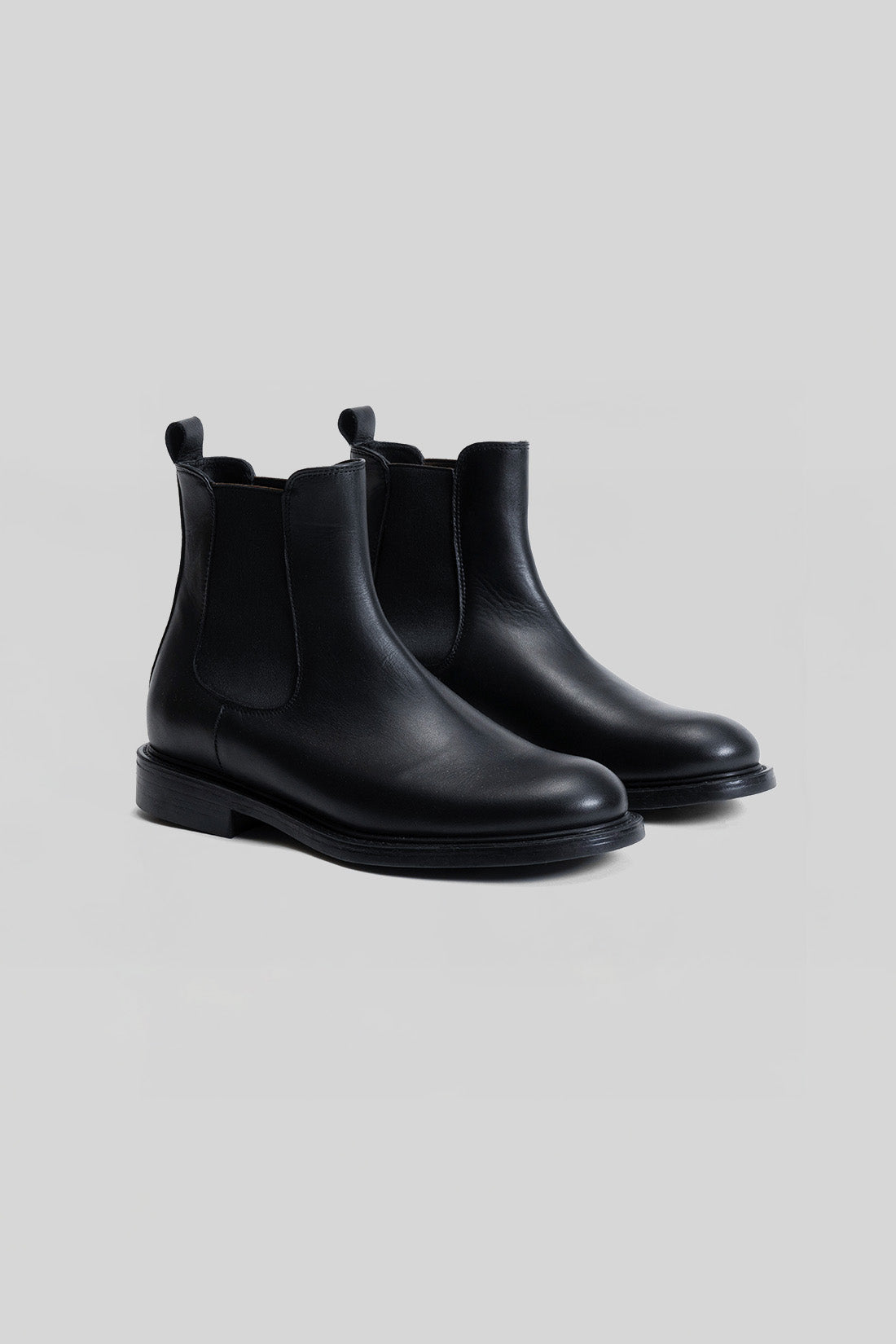 Black leather Chelsea boots with elastic side panels and thick rubber soles.