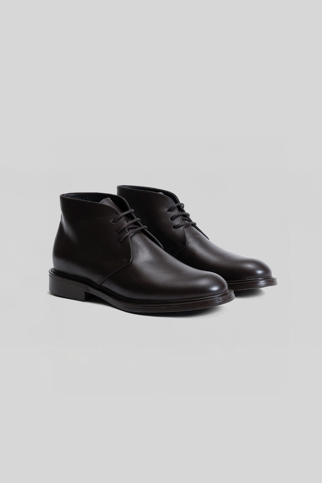 Black leather chukka boots with lace-up front and flat sole, shown as a pair.