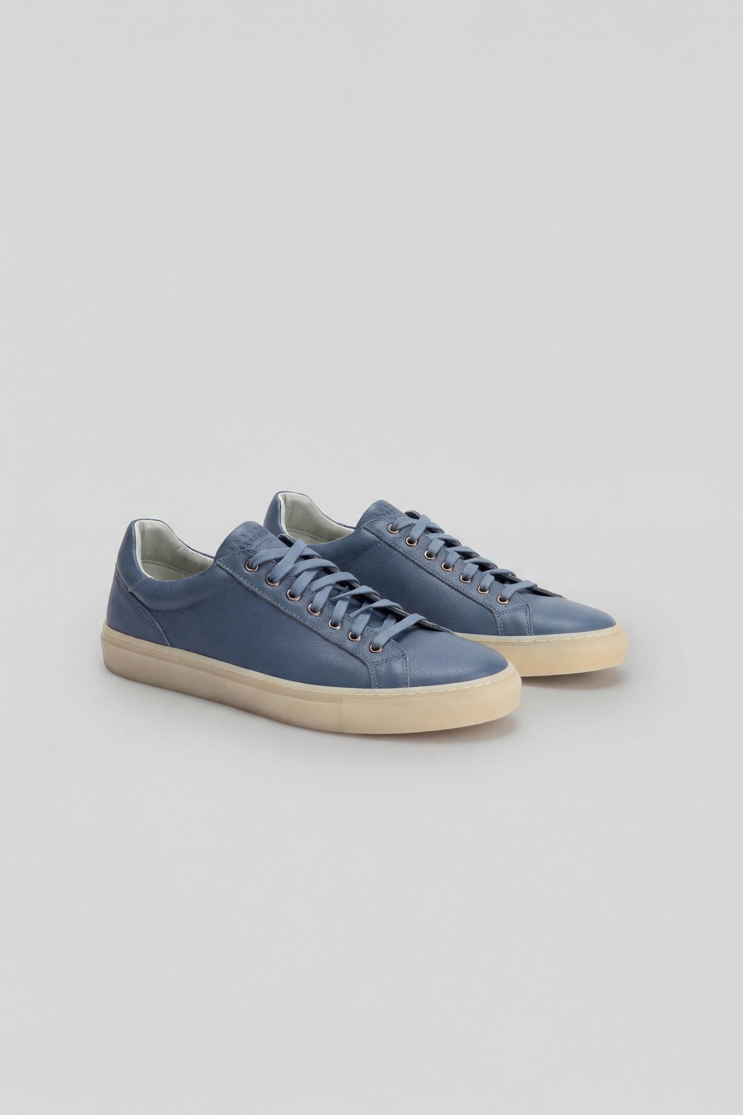 Navy blue leather sneakers with cream-colored sole and lace-up front closure.