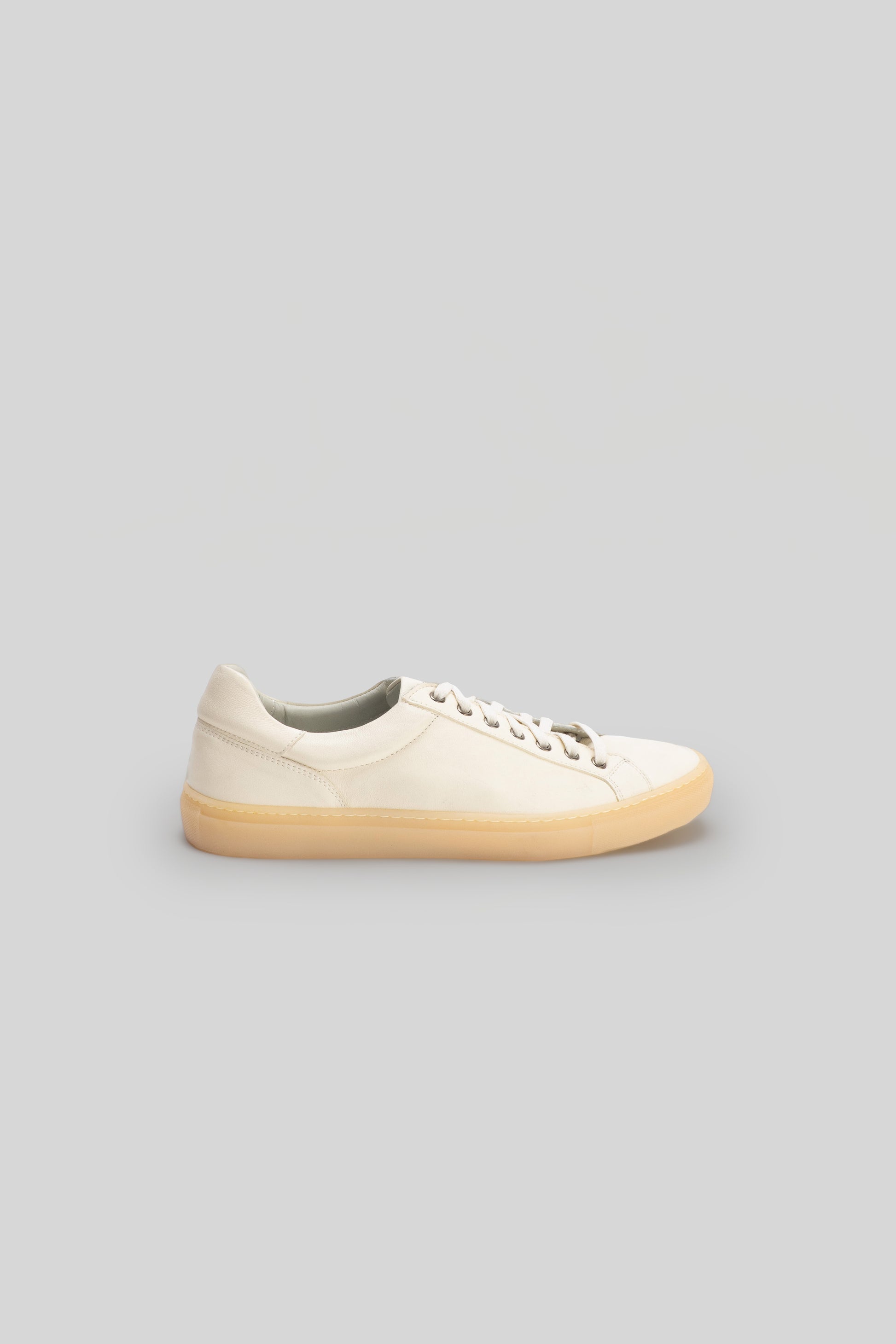 Cream leather low-top sneaker with cream laces and tan rubber sole, shown in profile view.