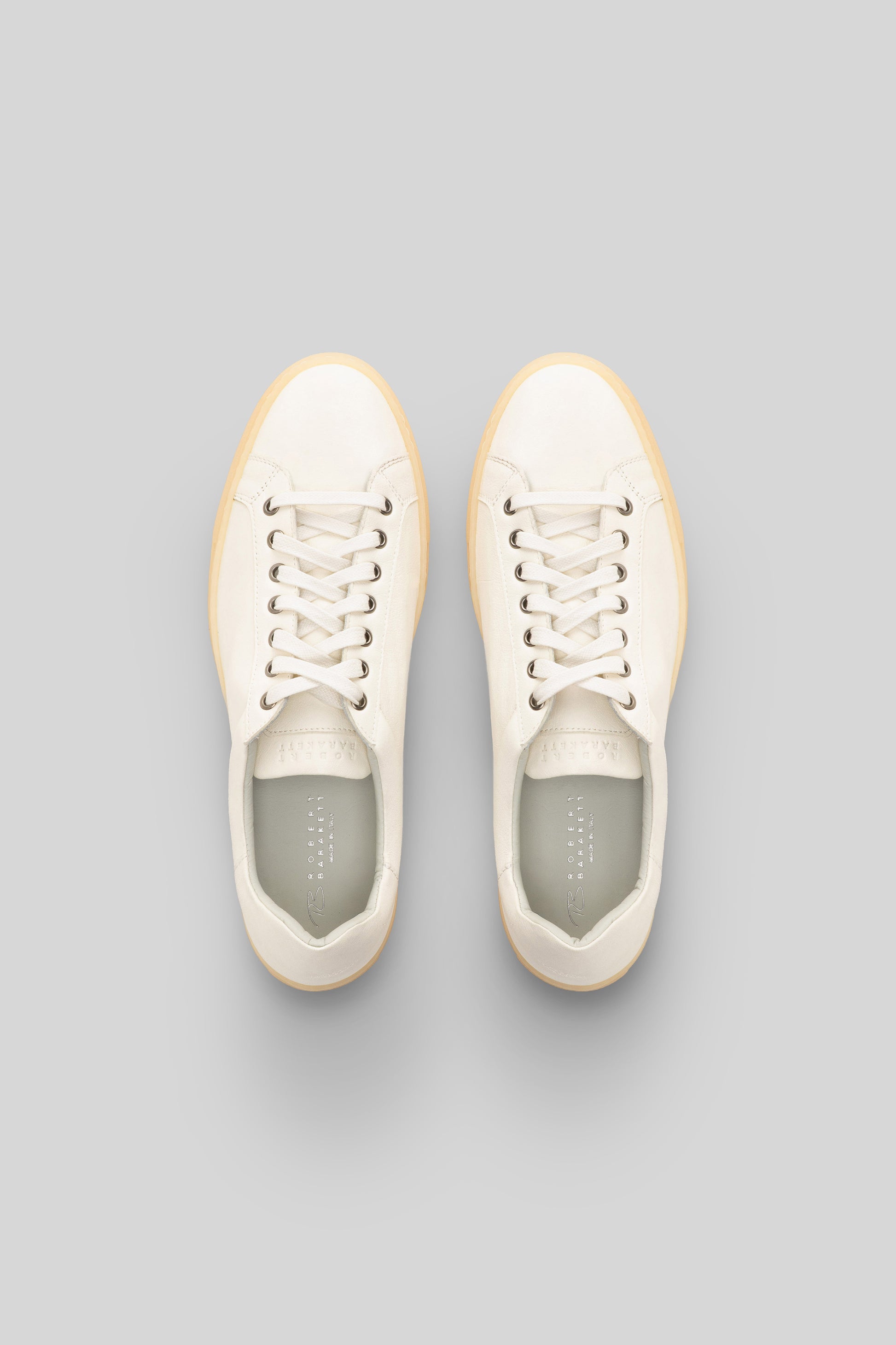 Cream leather sneakers with cream laces, tan rubber sole, and gray insoles shown from above.