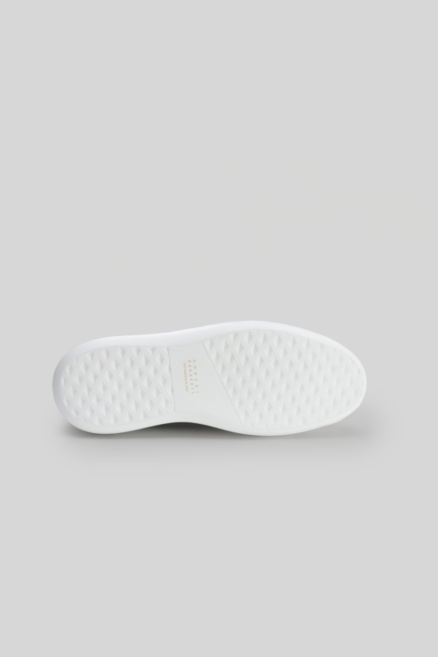 White textured rubber sole of a lace-up sneaker, viewed from underneath.