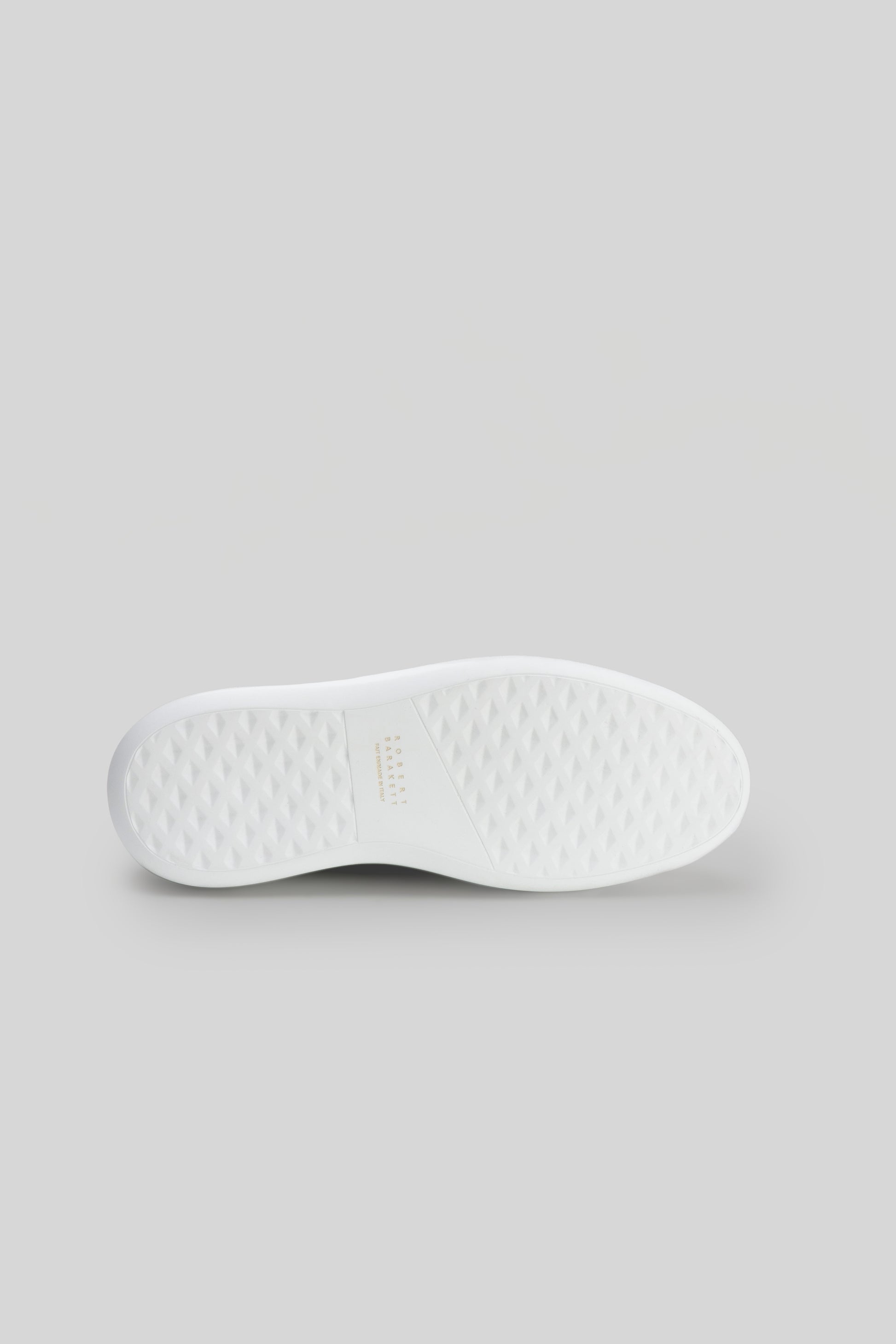 White textured rubber sole of a lace-up sneaker, viewed from underneath.