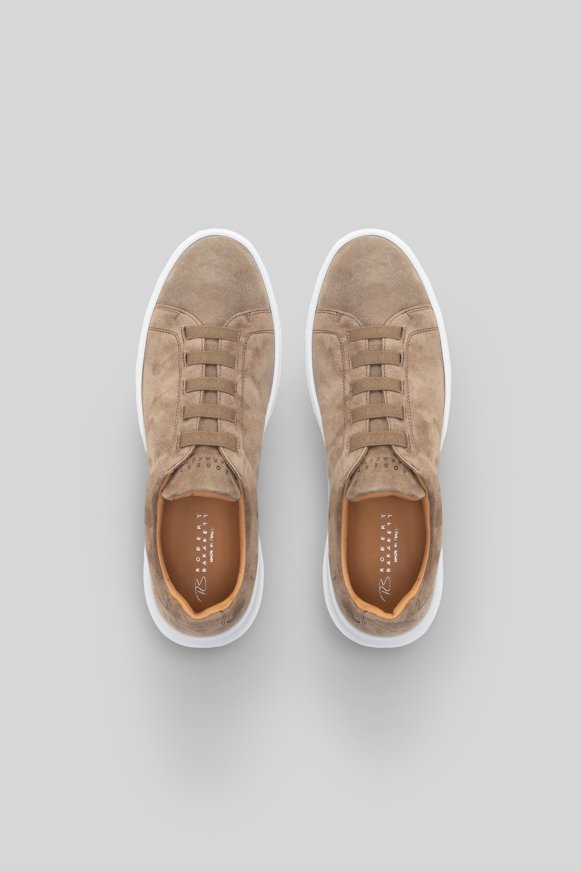 Beige suede sneakers with white sole and tan laces, shown from above.