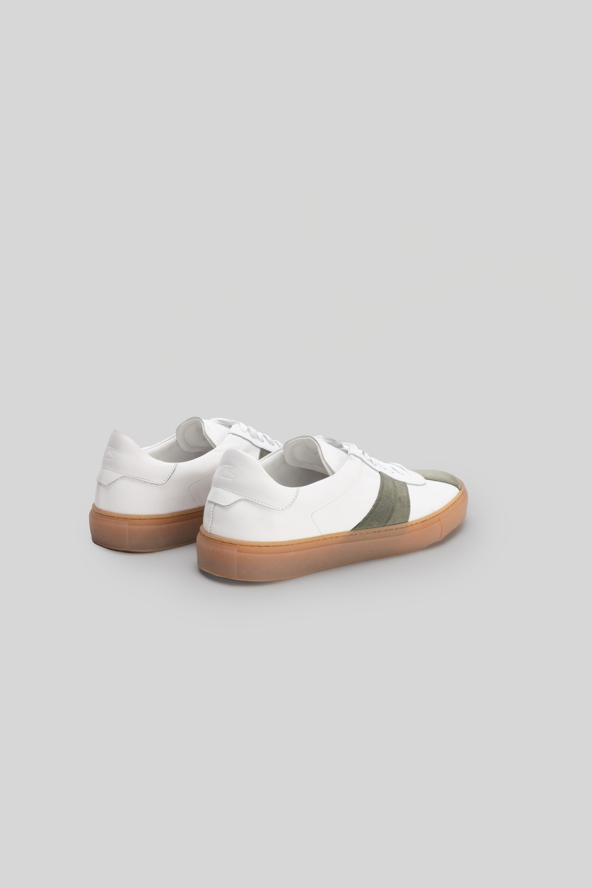 White leather sneakers with olive stripe detail and tan rubber sole, shown from rear view.